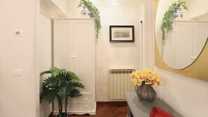 A hallway with a white door, a radiator, a framed picture on the wall, and a mirror with a gold frame. - L&D Suites 51, All Saints Square (Firenze)