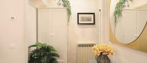 A hallway with a white door, a radiator, a framed picture on the wall, and a mirror with a gold frame.