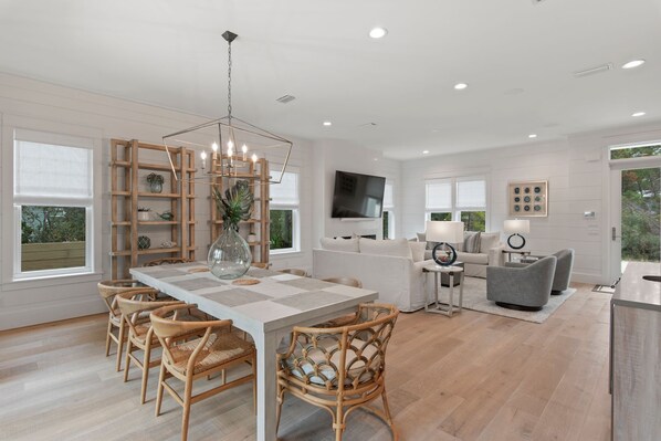 Una cocina moderna con una isla central, sillas de madera y una mesa de comedor.