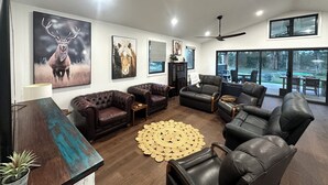 A modern living room with leather sofas, a coffee table, and artwork on the walls. - Riverfront Farm Stay with Animal Nursery at The Hatch Farm, Port Macquarie (Blackmans Point)