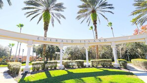 Un cartello con la scritta 'Emerald Island', palme e prati curati.