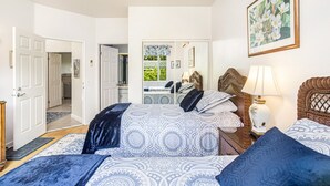 Un dormitorio con una cama grande, una mesita de noche con lámpara, un espejo y un cuadro en la pared.