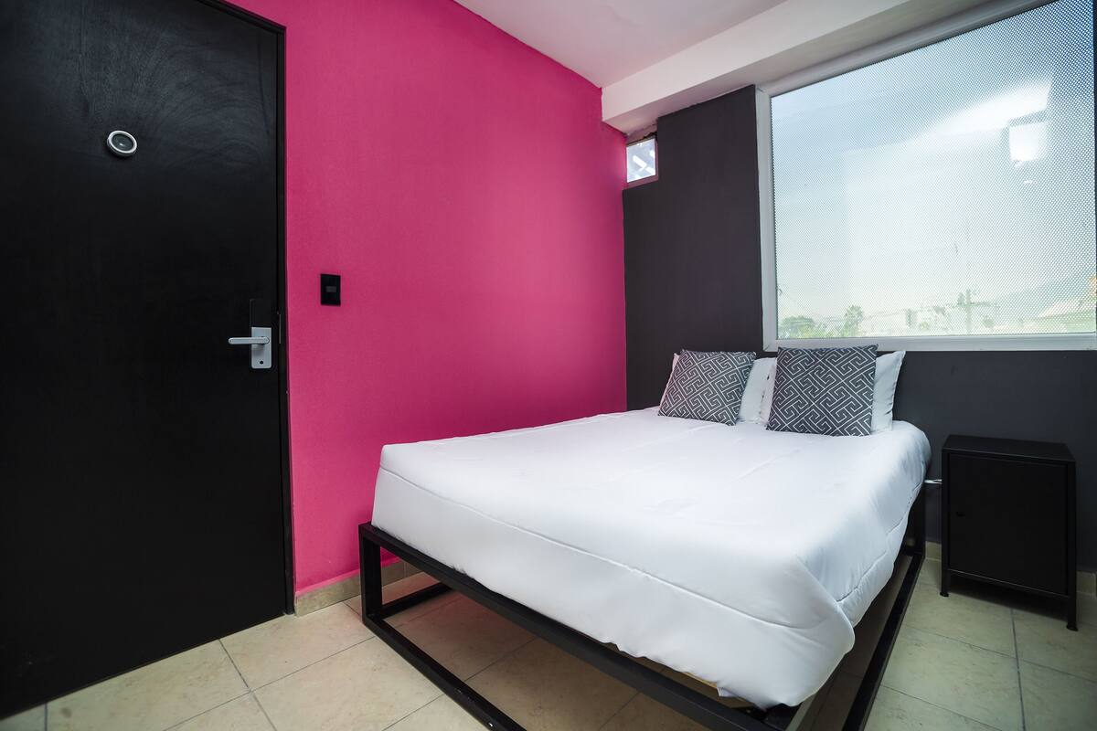 A bedroom with a bed, a window, and a door.