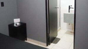 A hotel room with a bed, a small bedside table, a door leading to a bathroom, and a tiled floor. - Adhoc Cintermex (Monterrey)