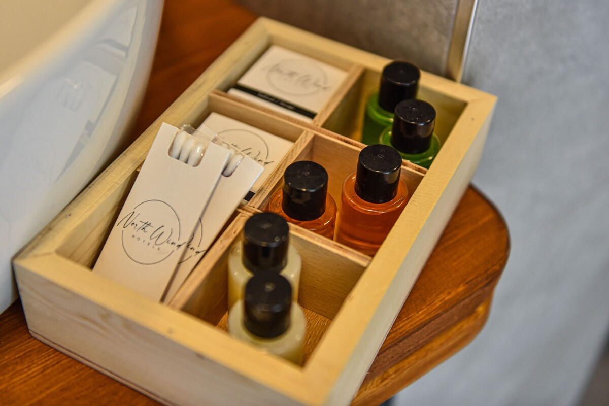 Una caja de madera con compartimentos que contienen artículos de tocador y una tarjeta de presentación.