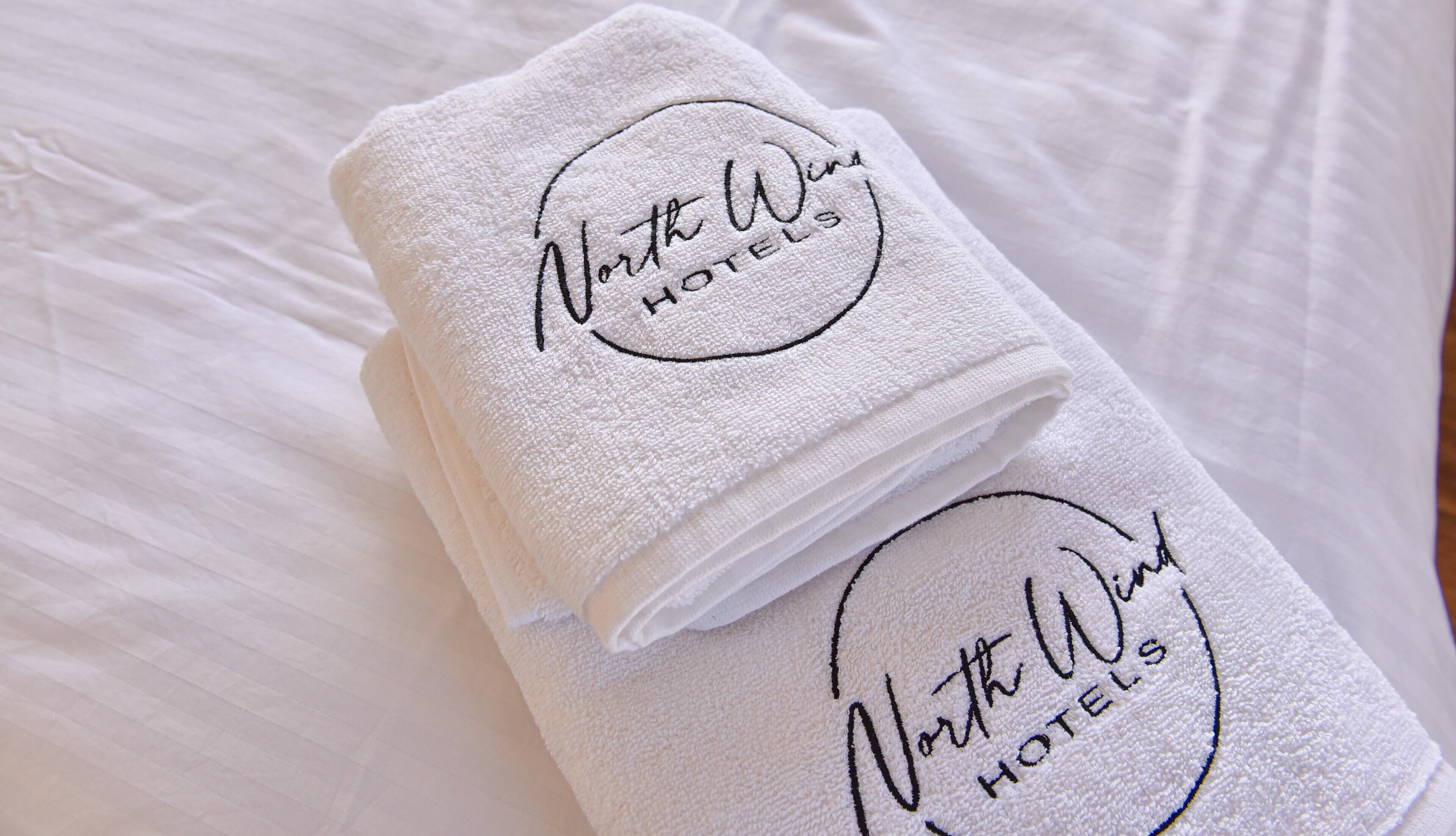 Two folded white towels with 'North West Hotels' embroidered on them.