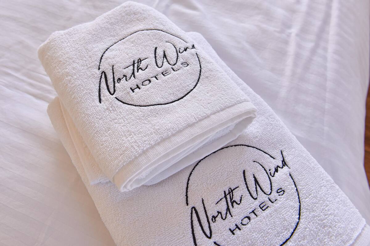 Dos toallas blancas dobladas con el bordado 'North West Hotels'.