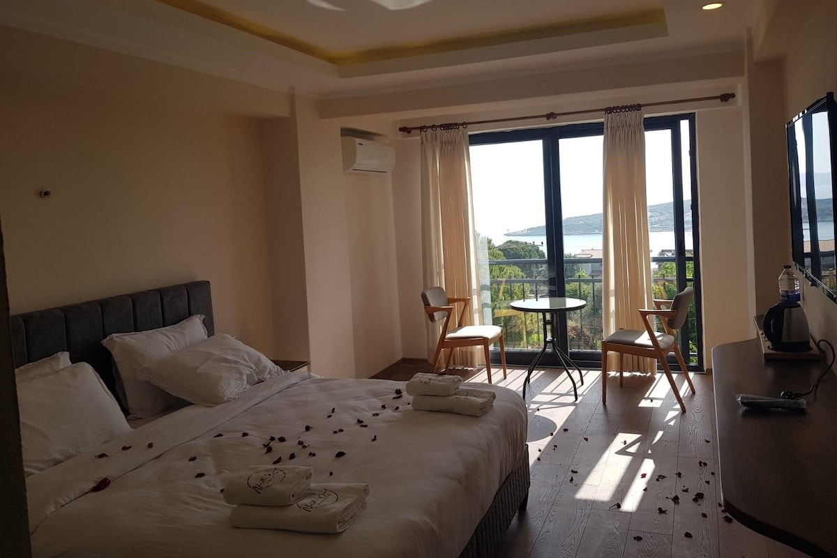 Ein Hotelzimmer mit Bett, einem Balkon mit Tisch und Stühlen und Meerblick.