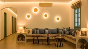 A cozy living room with a sofa, two side tables, and a bookshelf. - Armonia (Santorini)