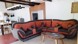 Ein modernes Wohnzimmer mit einer Eckcouch, einem runden Couchtisch und einem Essbereich mit Holztisch und Stühlen.