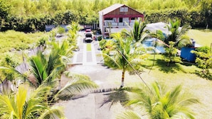 Ein Haus mit rotem Dach und weißen Wänden, umgeben von Palmen und einem Swimmingpool.