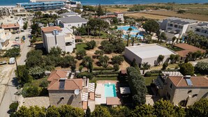 A coastal hotel with multiple buildings, a swimming pool, and a view of the sea.