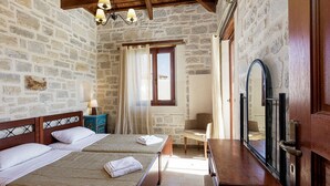 A room with two beds, a wooden headboard, a nightstand, a chair, a mirror, and a window with curtains.