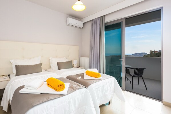 A hotel room with two beds, a balcony with a chair, and a view of the landscape.