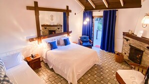 A cozy bedroom with a large bed, a smaller bed, a fireplace, and a dining area.
