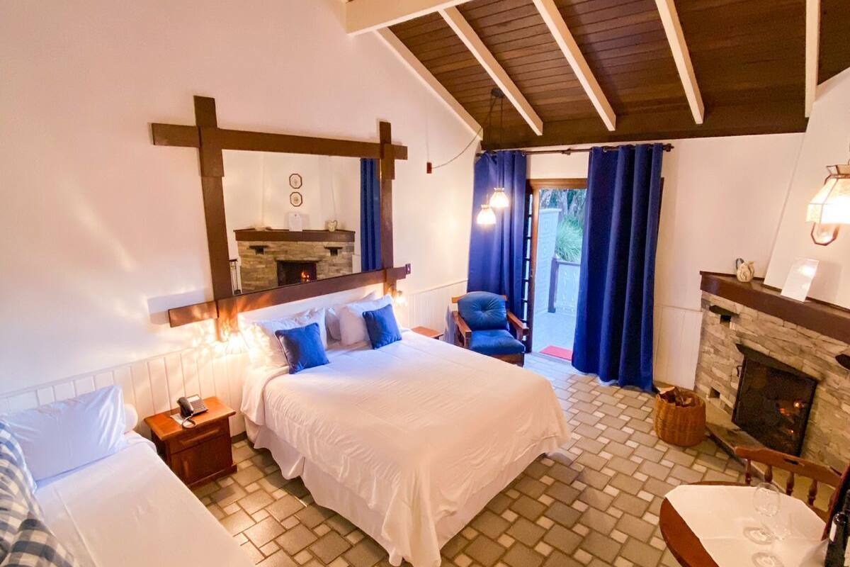 Un dormitorio acogedor con una cama grande, una cama más pequeña, una chimenea y un comedor.