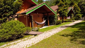 A row of wooden cabins with green roofs and a paved pathway leading to them.