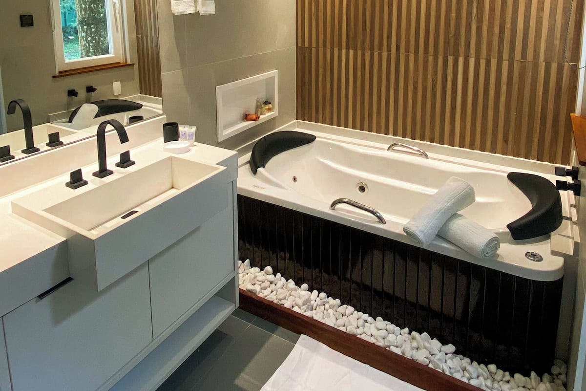 Un baño moderno con dos lavamanos, una bañera grande y un revestimiento de pared de madera.