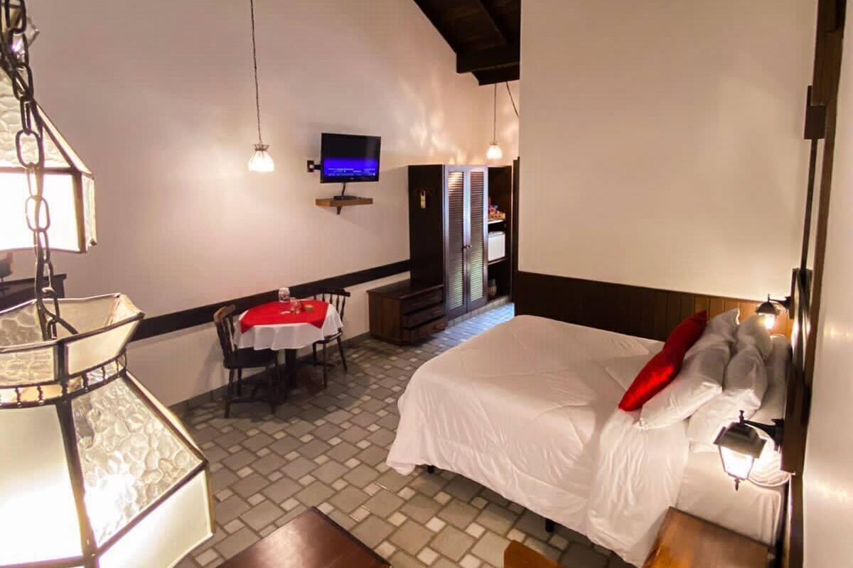 Una habitación de hotel con cama, televisor, zona de comedor y candelabro.