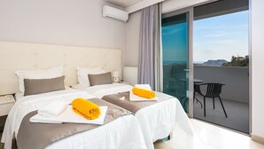 Ein Hotelzimmer mit zwei Betten, einem Balkon mit einem Stuhl und Blick auf die Landschaft.