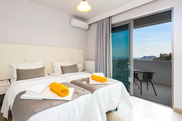 A hotel room with two beds, a balcony with a chair, and a view of the landscape.