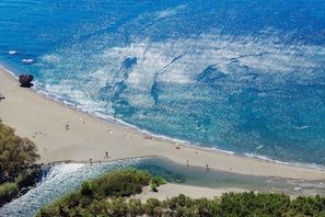 A beach with clear water, people, and trees.