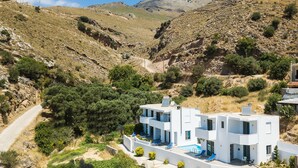 Ein modernes, zweistöckiges Gebäude mit Swimmingpool, eingebettet in eine gebirgige Landschaft.