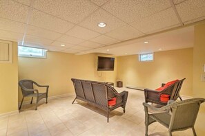 A room with three wicker chairs, a flat-screen TV mounted on the wall, and a small table. - Book Eastham, Plenty Of Room For Entire Family! (Eastham)