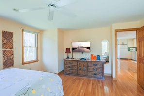 Ein Schlafzimmer mit Bett, Schminktisch, Fernseher und Deckenventilator.