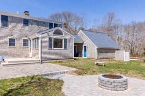 A two-story house with a covered porch, a fire pit, and a paved driveway. - Book Eastham, Plenty Of Room For Entire Family! (Eastham)