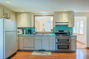 A compact kitchen with white cabinets, a built-in oven, a microwave, and a sink.
