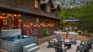 Une maison en bois dotée d’un bain à remous, d’un espace salon extérieur et d’une terrasse couverte.