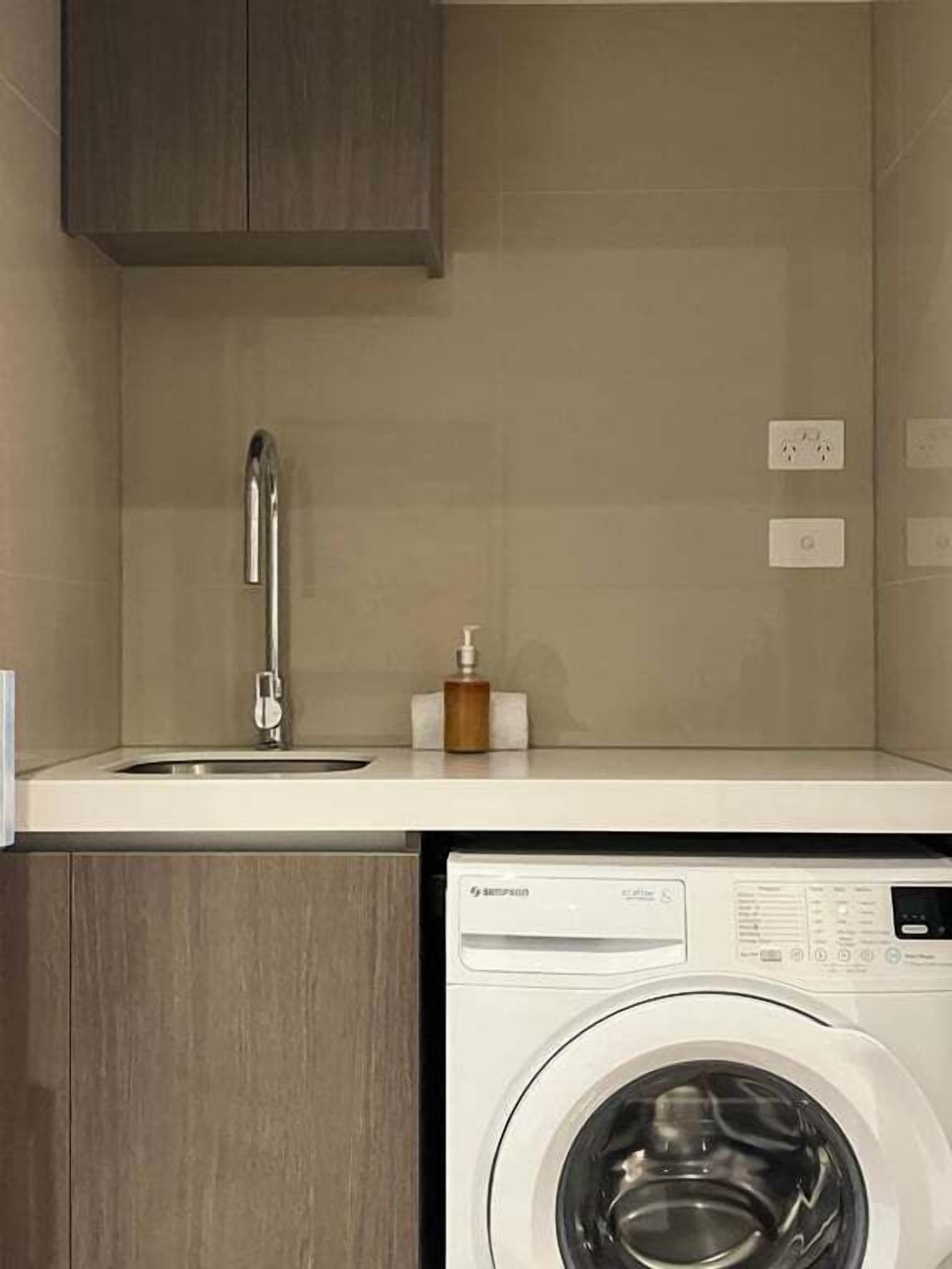 A compact kitchen with a built-in washing machine, a sink, and a cabinet.