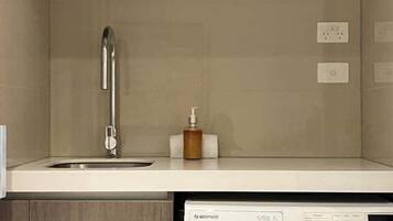 A compact kitchen with a built-in washing machine, a sink, and a cabinet.