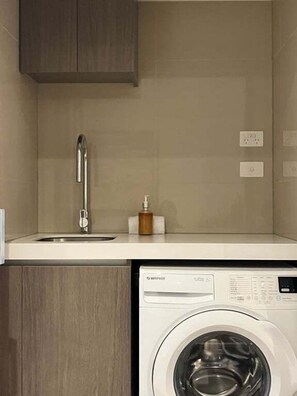 A compact kitchen with a built-in washing machine, a sink, and a cabinet.