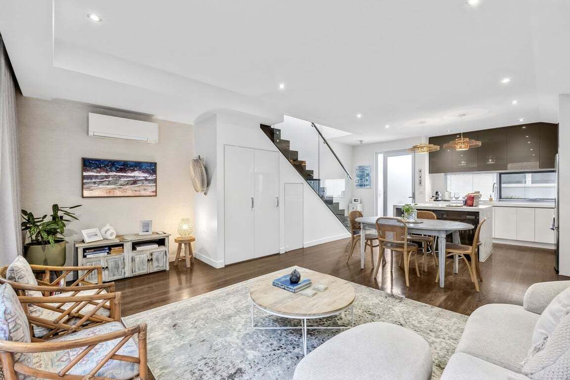 Una sala de estar moderna con una escalera, un comedor y una cocina.