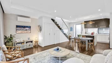 Una sala de estar moderna con una escalera, un comedor y una cocina.