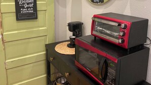 A kitchen with a vintage black microwave, a coffee maker, and a sign reading "Welcome! Be our Guest." - Disney,Busch Gardens,Beautiful Beaches 1-bedroom studio, 15 minutes from Tampa. (Land O' Lakes)