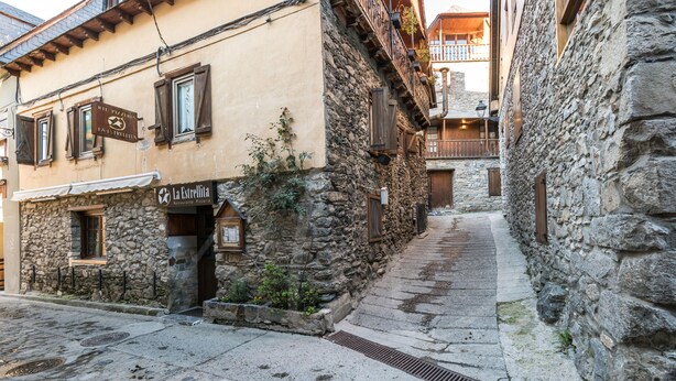 A narrow street with stone buildings, one with a sign reading "La Estrellita".