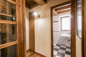 Ein Badezimmer mit Holzrahmen, einem Schachbrettfußboden, einem Waschbecken und einem Fenster über dem Spiegel.