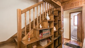 A wooden staircase with built-in shelves holding books, decorative items, and a small bird figurine.