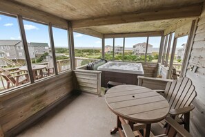 Eine Holzterrasse mit Whirlpool, Tisch und Stühlen.