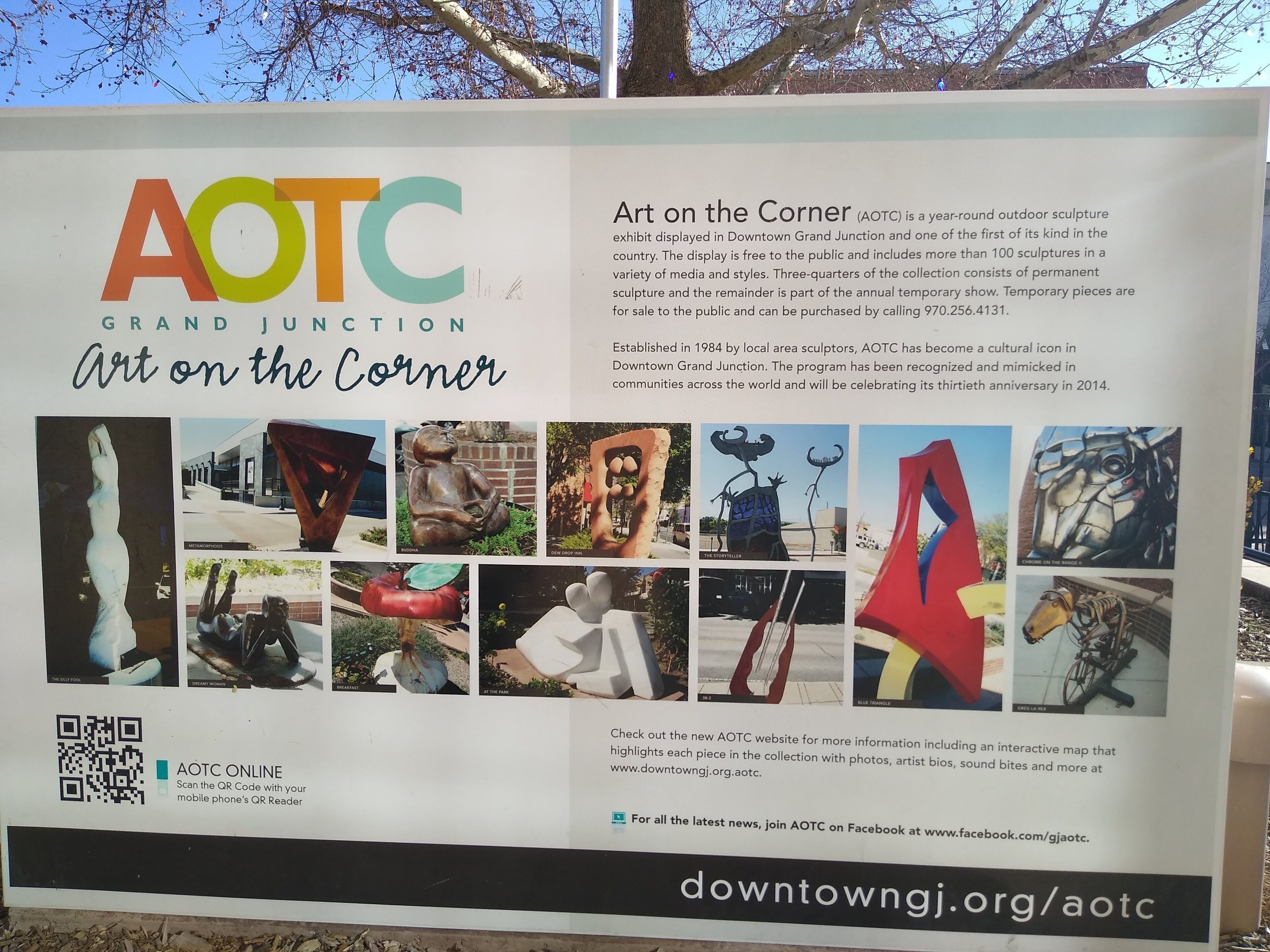 A signboard for Art on the Corner (AOTC) in Downtown Grand Junction, featuring a QR code and a list of sculptures.