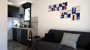 Ein kompakter Wohnraum mit Küchenzeile, einer Couch und abstrakter Wandkunst.