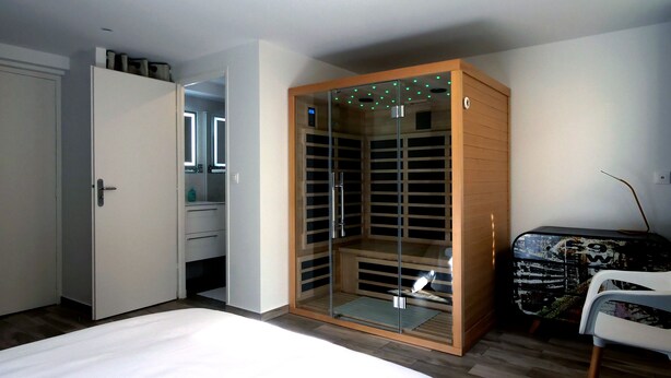 Ein Schlafzimmer mit begehbarem Kleiderschrank, einem Bett und einem Sessel.