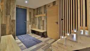A modern room with a wooden floor, a dark door, a bench, and a wooden partition with vertical slats.