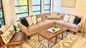 A modern living room with a sectional sofa, a coffee table, and a patterned rug. - North Captiva Island- Ocean bay views and modern decor. Two new carts! (Captiva)
