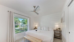A bedroom with a bed, bedside tables, a bench, a ceiling fan, and a window with curtains. - North Shore Very Walkable to Ami fun (Anna Maria)