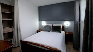 A neatly arranged hotel room with a bed, bedside tables, a headboard with integrated lighting, a wardrobe, and a window with curtains. - T2 Orly center ville Close to Paris and shops (Orly)