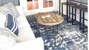 Un salon doté d’un ventilateur de plafond, d’un canapé agrémenté de coussins à motifs, d’une table basse et d’un téléviseur fixé au mur.